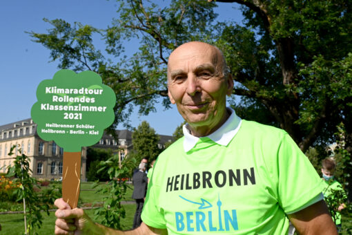 Der Radfahrer und Initiator des Aktion «rollendes Klassenzimmer», Ortwin Czarnowski, steht bei einem Pressetermin mit dem Logo der Klimaschutzaktion vor dem Stuttgarter Landtag.